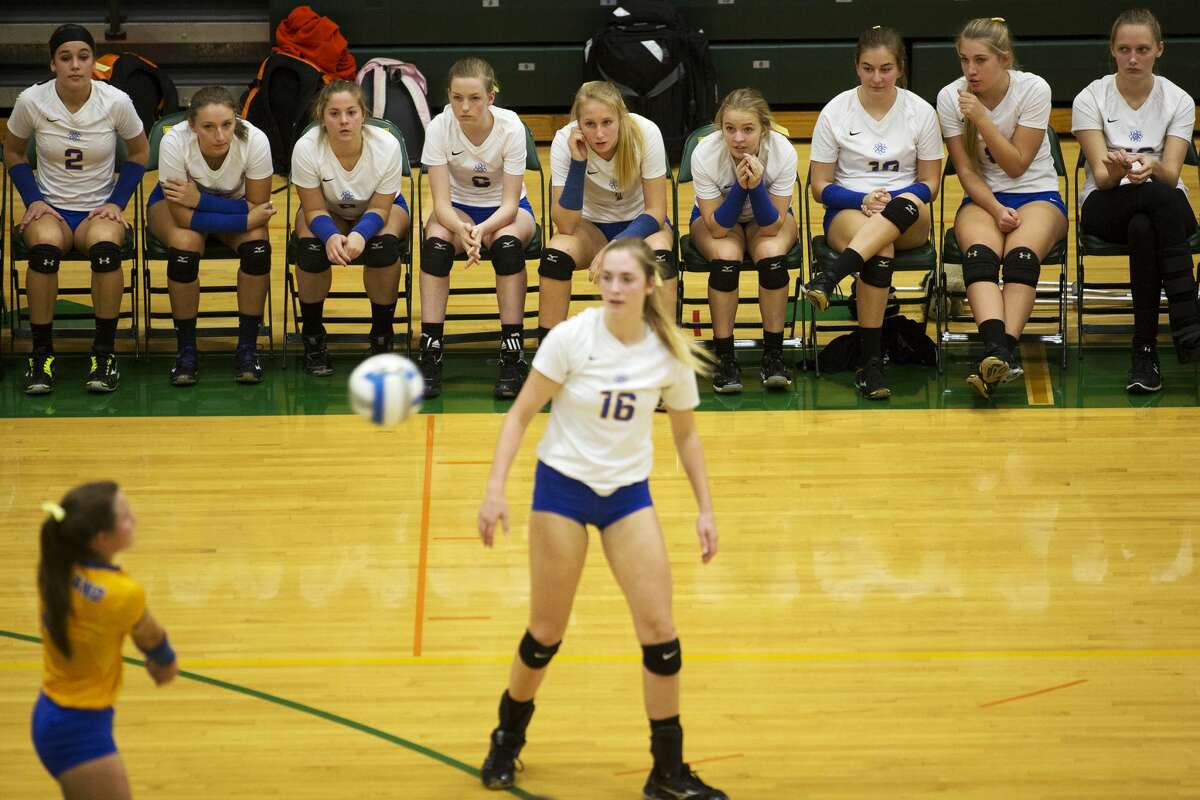 Midland High School senior Julia Gross hits the ball toward Fenton High School while her teammates watch from the bench in the Class A volleyball quarterfinals at Dow High School on Tuesday.