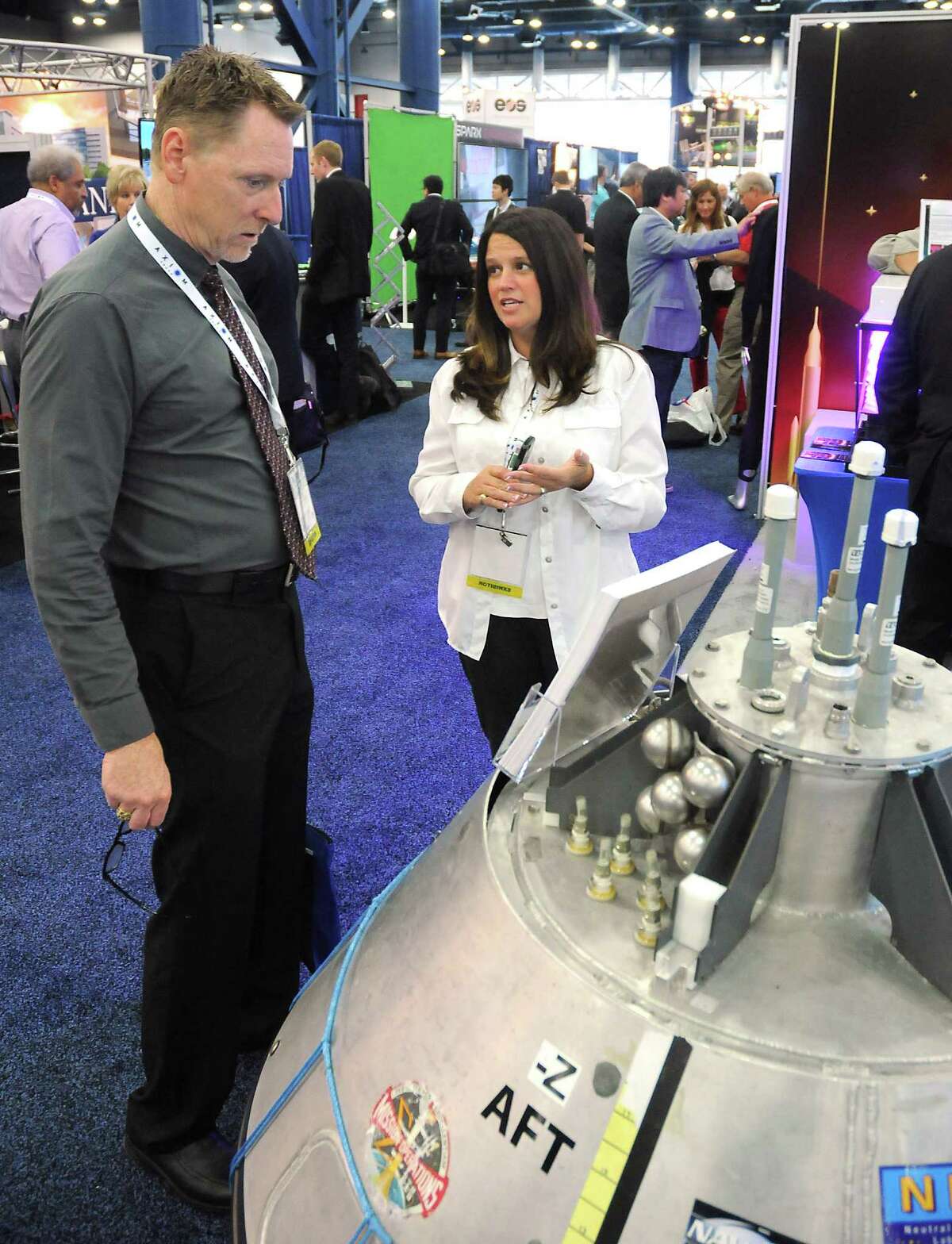 Angela Prince from NASA's Neutral Buyoncy Lab talks to fellow NASA employee Jerry Condon near a training capsule at SpaceCom at the George R. Brown Convention Center Wednesday Nov. 16, 2016.(Dave Rossman photo)