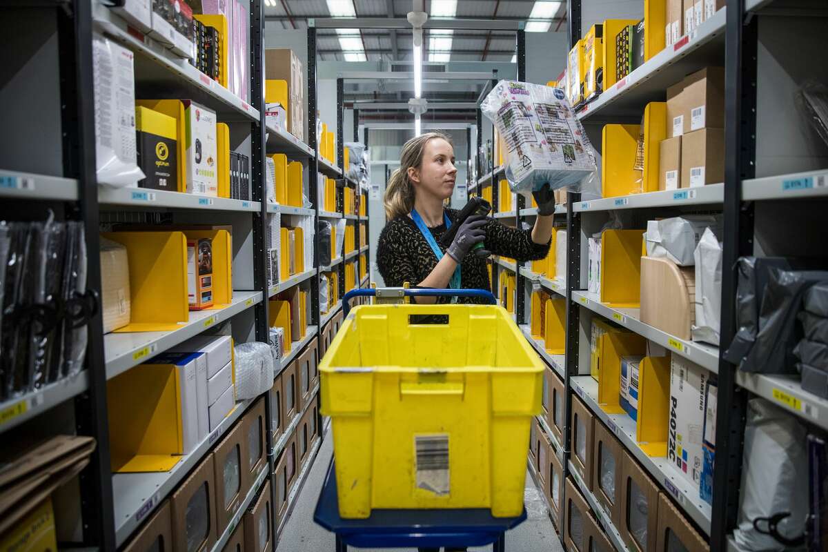 An employee scans merchandise as she collects items for a customer's delivery order from an Amazon.com Inc. fulfillment center in Peterborough, U.K., on Tuesday, Nov. 15, 2016. The online retail giant needs smart engineers to help expand its cloud computing division, automate warehouses and develop new gadgets like the voice activated Echo speaker. Photographer: Simon Dawson/Bloomberg