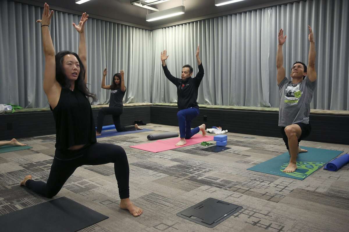 Yoga instructor Kim Sin (left) leads a class for employees in a conference room at Ancestry.com on Townsend Street in San Francisco, Calif. on Thursday, Nov. 17, 2016.