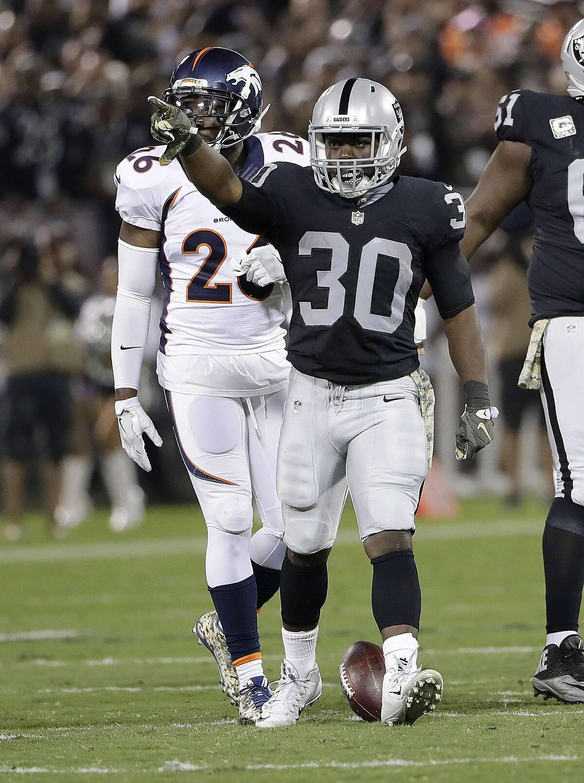Oakland Raiders running back Jalen Richard (30) gestures in front of Denver Broncos free safety Darian Stewart (26) during the first half of an NFL football game in Oakland, Calif., Sunday, Nov. 6, 2016. (AP Photo/Marcio Jose Sanchez)