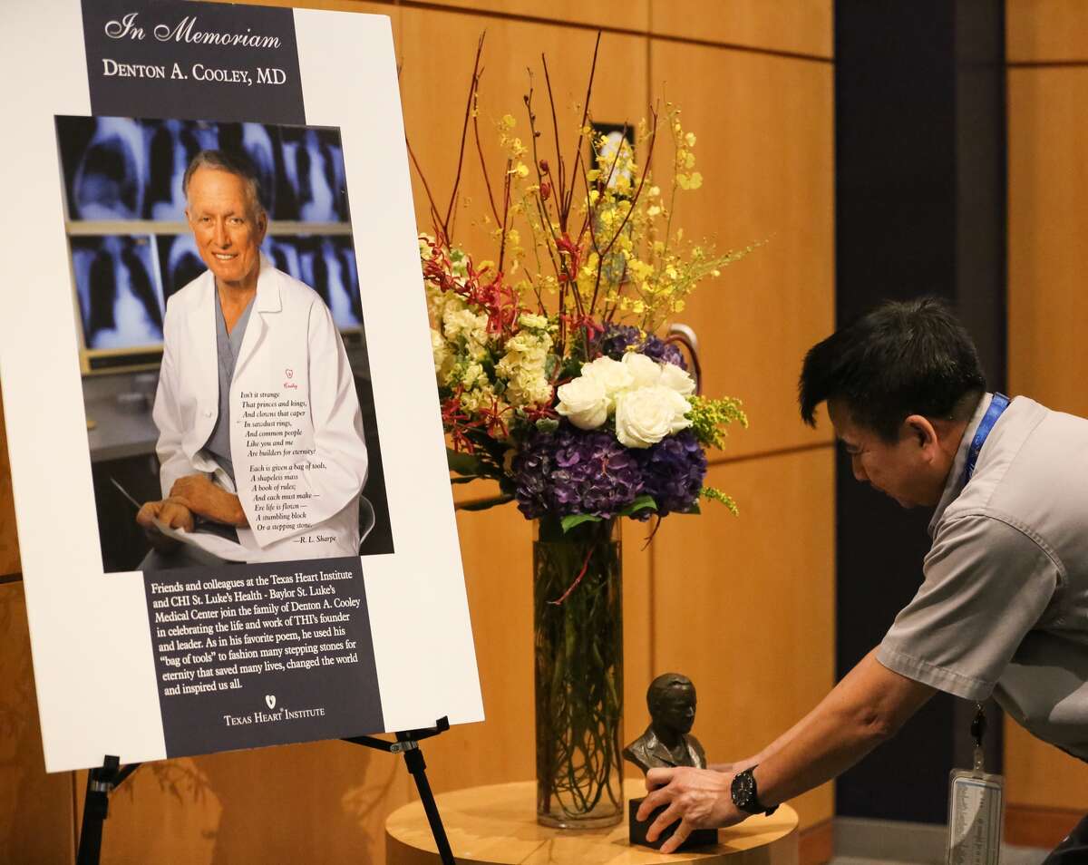 Texas Children's Hospital worker Phong Nguyen straightens a statue of Dr. Denton Cooley at a memorial honoring the pioneering surgeon at Texas Children's Heart Center on Friday.