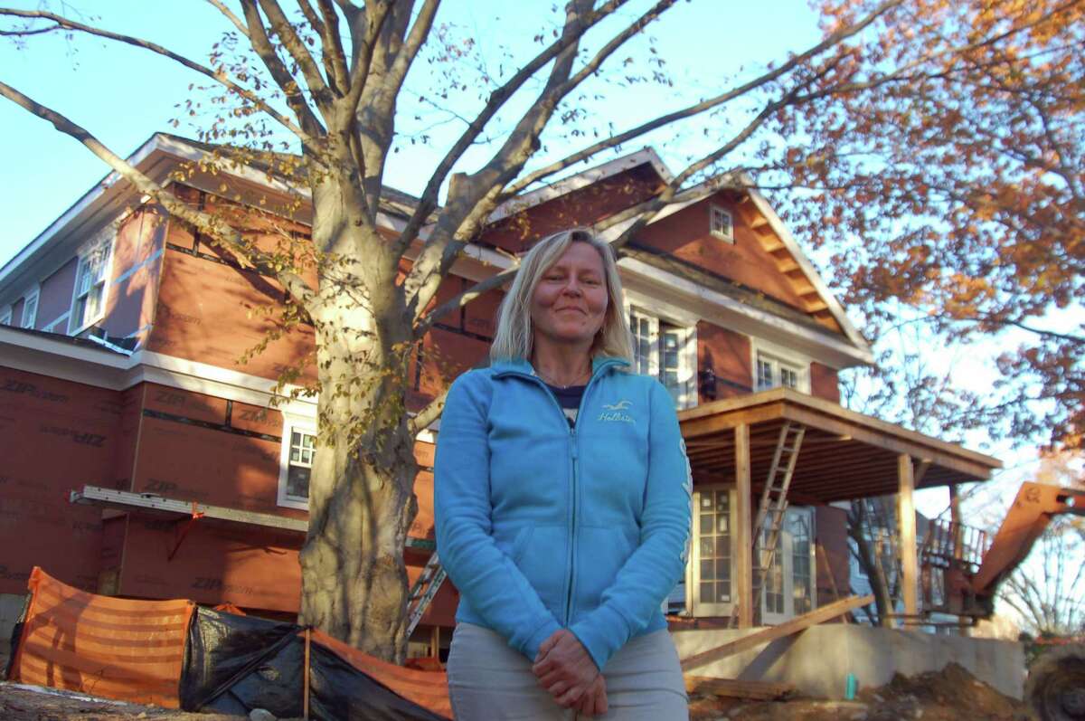 Old Greenwich resident Chris Katsigiannis stands before a house she owns on Northridge Road. The home is being rebuilt after fire destroyed it. Katsigiannis fought to save the copper beech tree, behind her, from being cut down during the building process.