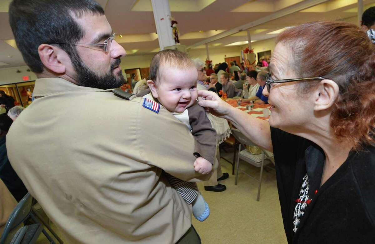 Bassam El-Abid of Boy Scout Troop 19 holds his smiling 3.5-month-old son, Omar, as Gail Kantzan gives him a tickle during the Community Thanksgiving Luncheon at Cornerstone Community Church on Sunday. Turkey and all the trimmings were served up to about 300 people by church members and volunteers. It was the 17th year for the event.