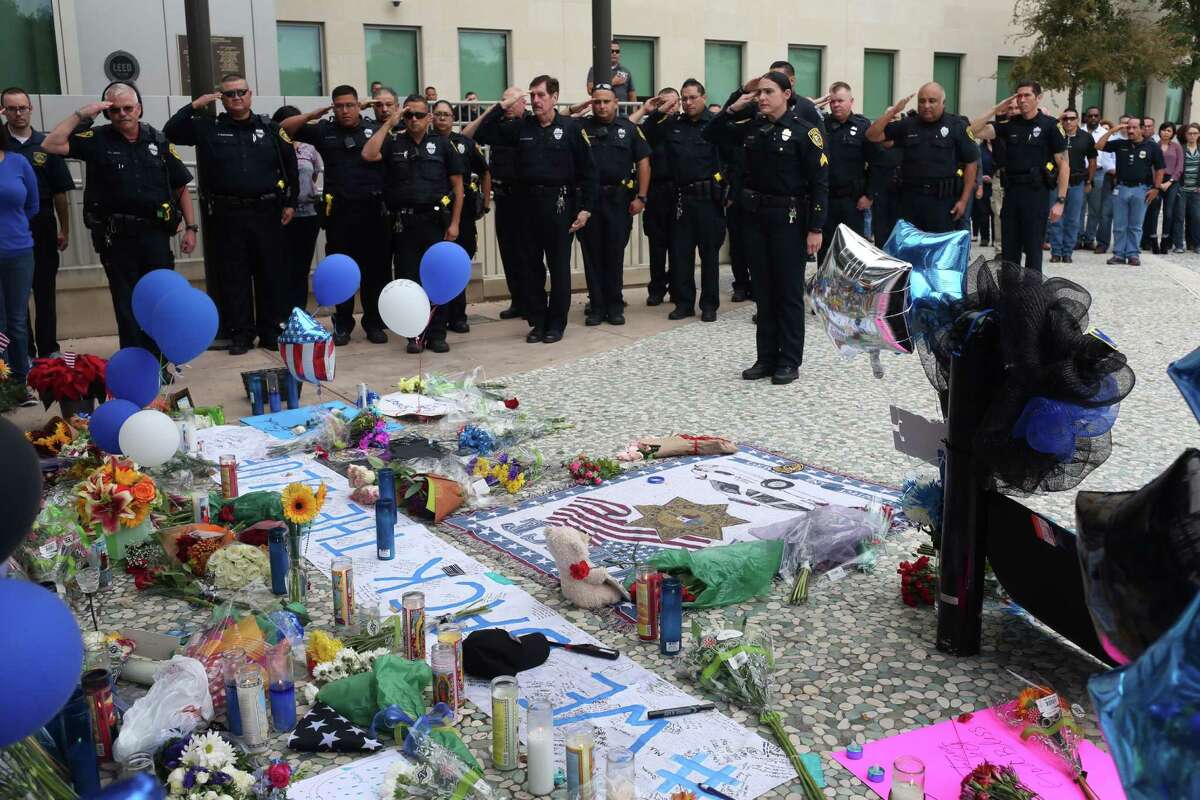 Bexar County Sheriff's Office deputies and personnel salute at the makeshift memorial for slain San Antonio Police Department Detective Benjamin Marconi in front of police headquarters Tuesday morning.