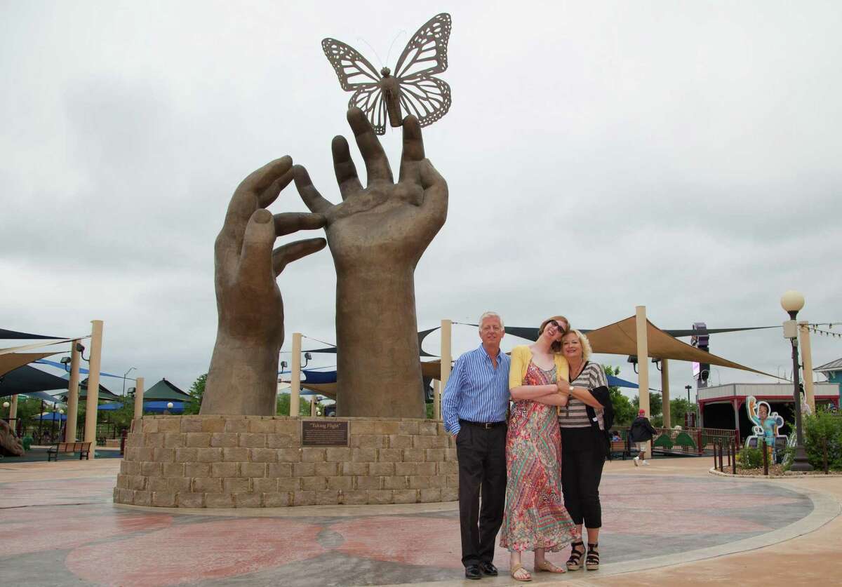 Morgan’s Wonderland founder Gordon Hartman, daughter Morgan and wife/mother Maggie Hartman pose by the large sculpture of hands and a butterfly just inside the theme park for people with special needs. More more information on the park in San Antonio, go to morganswonderland.com.