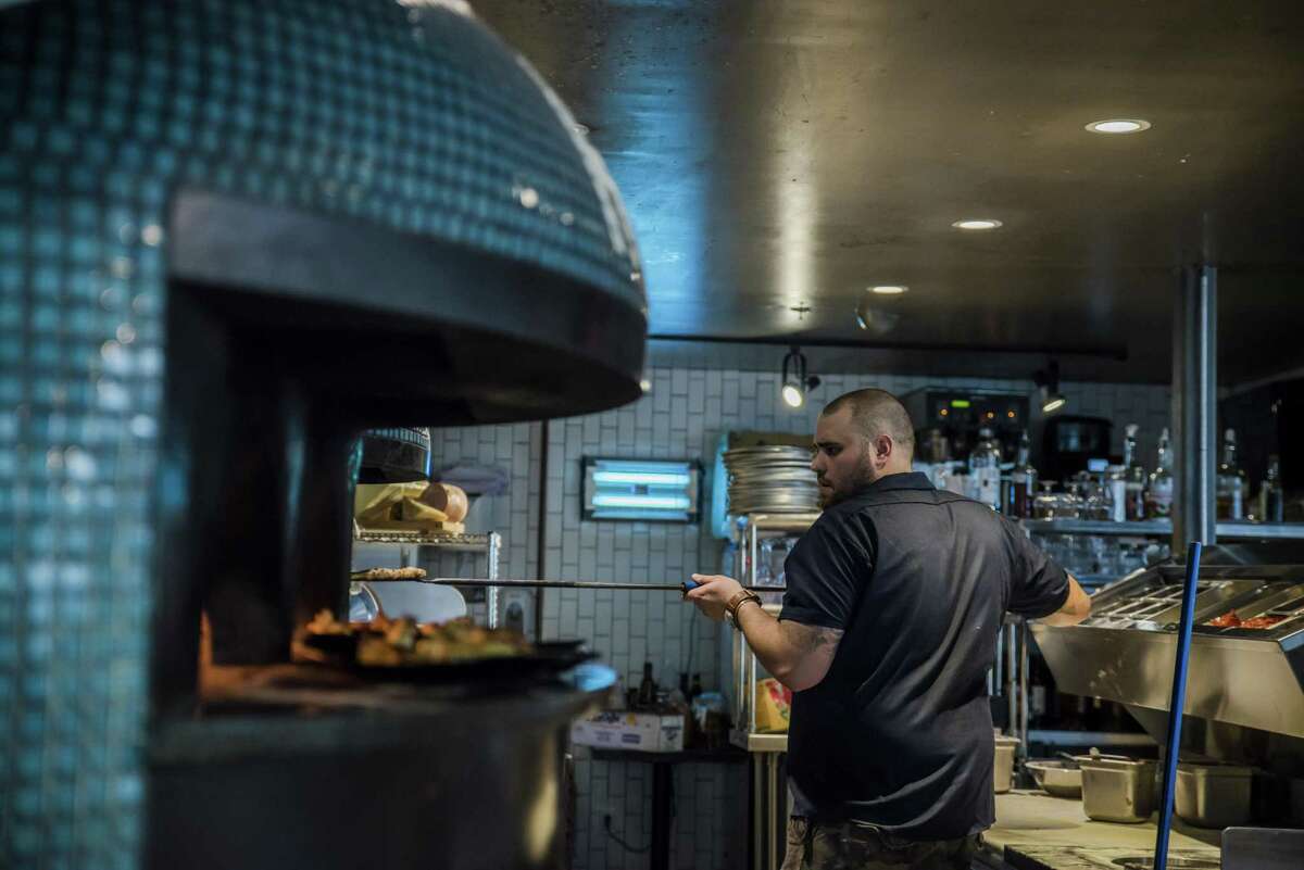 Chef Christian Petroni reaches into one of two stone pizza ovens in his restaurant, Fortina.