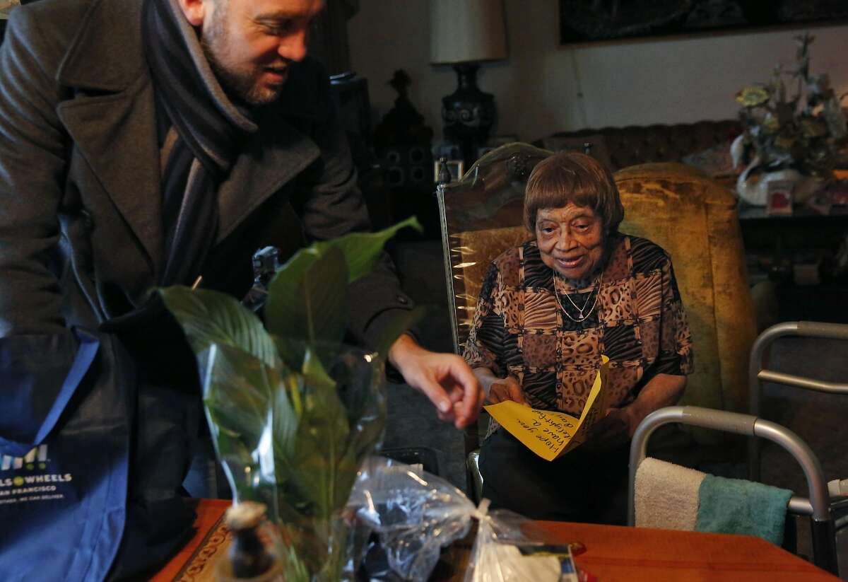 Maggie Agee, 90, looks over her food and gift bag delivery from Karl Robillard from Meals on Wheels in her home Nov. 24, 2016 in San Francisco, Calif.