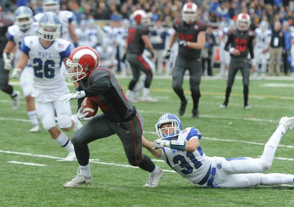 New Canaan's Quintin O'Connell (20) slips away from Darien defensive back Timothy Herget (31) to score a touchdown in Darien's 37-34 win over New Canaan in the Turkey Bowl high school football game at Dunning Stadium in New Canaan, Conn. Thursday, Nov. 24, 2016. New Canaan scored 24 unanswered points to tie the game and force an overtime. In overtime, Darien kicked a field goal to take the lead and forced a New Canaan interception to end the game, setting off a wild celebration as fans stormed the field.