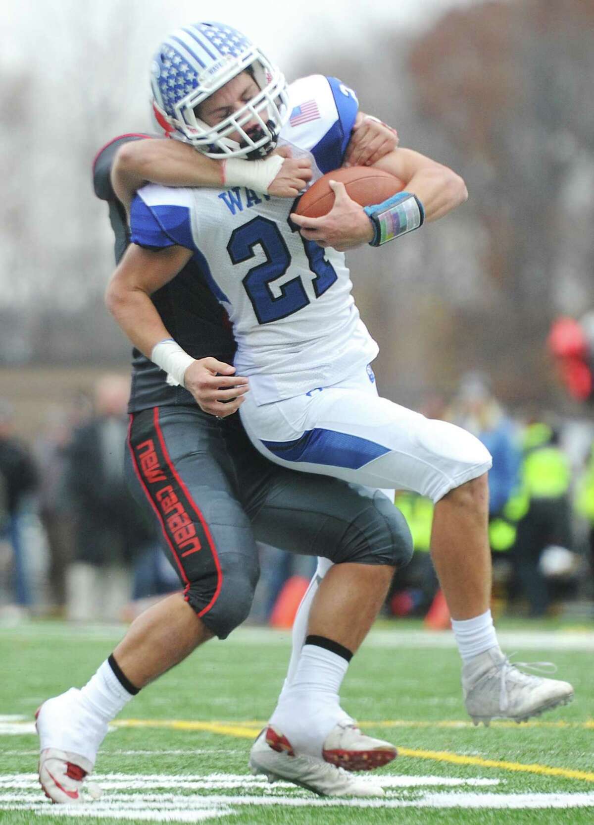Darien's Mitchell Pryor (21) runs with a New Canaan defender on his back in Darien's 37-34 win over New Canaan in the Turkey Bowl high school football game at Dunning Stadium in New Canaan, Conn. Thursday, Nov. 24, 2016. New Canaan scored 24 unanswered points to tie the game and force an overtime. In overtime, Darien kicked a field goal to take the lead and forced a New Canaan interception to end the game, setting off a wild celebration as fans stormed the field.