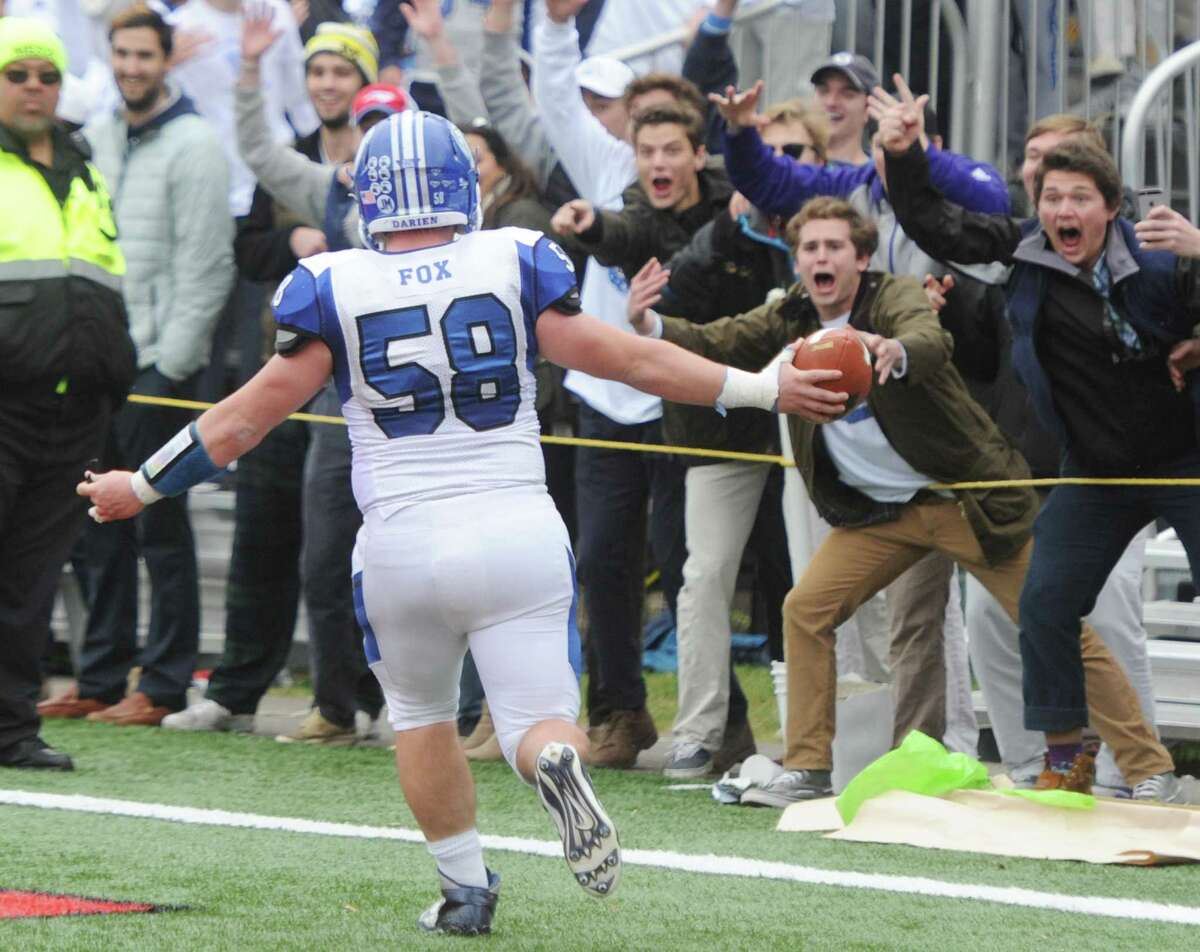 Below, fans cheer after Cord Fox scored a defensive touchdown in Darien's 37-34 win over New Canaan in the Turkey Bowl high school football game at Dunning Stadium in New Canaan, Conn. Thursday, Nov. 24, 2016. New Canaan scored 24 unanswered points to tie the game and force an overtime. In overtime, Darien kicked a field goal to take the lead and forced a New Canaan interception to end the game, setting off a wild celebration as fans stormed the field.