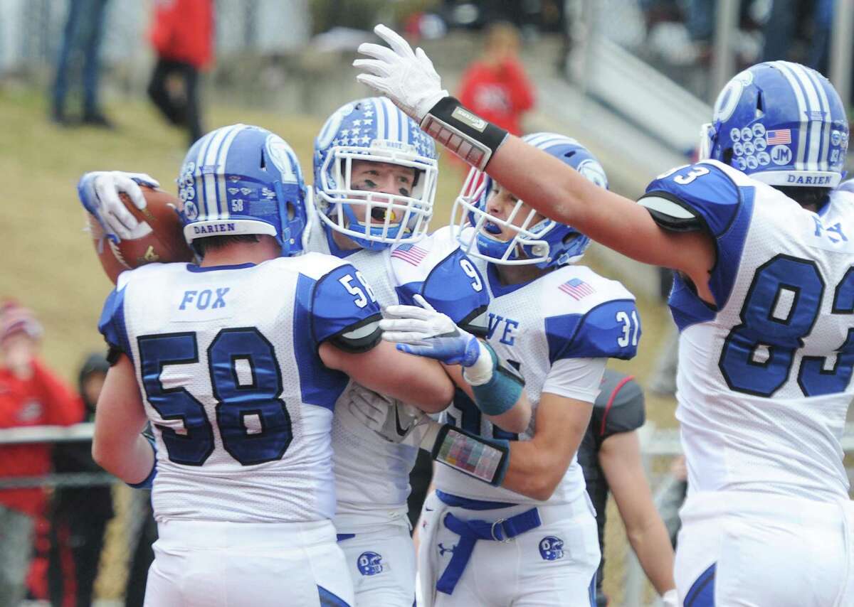 Darien's Finlay Collins, center, celebrates a touchdown with teammates Cord Fox (58), Timothy Herget (31), and Quinlin Fay (83) in Darien's 37-34 win over New Canaan in the Turkey Bowl high school football game at Dunning Stadium in New Canaan, Conn. Thursday, Nov. 24, 2016. New Canaan scored 24 unanswered points to tie the game and force an overtime. In overtime, Darien kicked a field goal to take the lead and forced a New Canaan interception to end the game, setting off a wild celebration as fans stormed the field.
