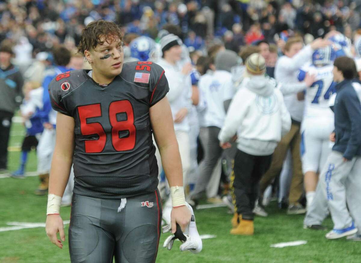 New Canaan's Teddy Hood walks off as Darien storms the field after its 37-34 win over New Canaan in the Turkey Bowl high school football game at Dunning Stadium in New Canaan, Conn. Thursday, Nov. 24, 2016. New Canaan scored 24 unanswered points to tie the game and force an overtime. In overtime, Darien kicked a field goal to take the lead and forced a New Canaan interception to end the game, setting off a wild celebration as fans stormed the field.