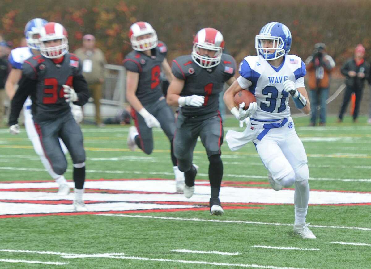 Darien’s Timothey Herget, above right, breaks a long run in the Blue Wave’ 37-34 win over New Canaan in the Turkey Bowl Thursday at Dunning Stadium in New Canaan.