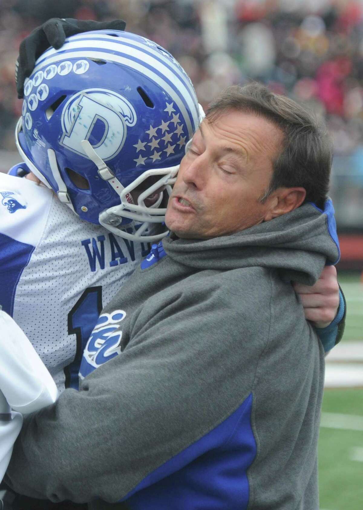 Darien head coach Rob Trifone congratulates a player during Darien's 37-34 win over New Canaan in the Turkey Bowl high school football game at Dunning Stadium in New Canaan, Conn. Thursday, Nov. 24, 2016. New Canaan scored 24 unanswered points to tie the game and force an overtime. In overtime, Darien kicked a field goal to take the lead and forced a New Canaan interception to end the game, setting off a wild celebration as fans stormed the field.