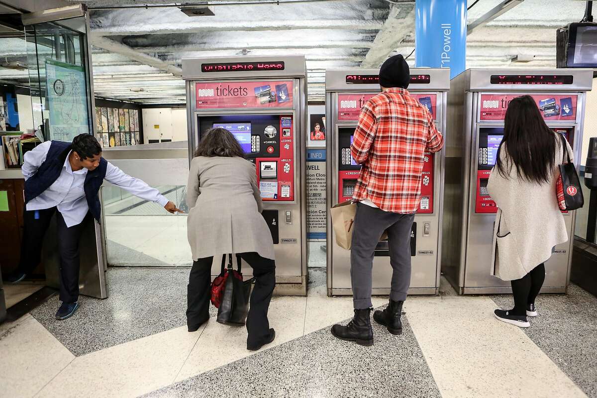 A Muni attendant helps as passengers purchase Muni tickets from kiosks at Powell Station on Monday, November 29, 2016.