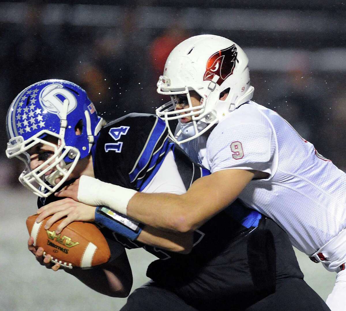 At left, Darien quarterback Brian Peters (14) is sacked by Ian Pearson (9) of Greenwich during the Class LL high school football playoff game between Greenwich High School and Darien High School at Stamford High School, Conn., Tuesday night, Nov. 29, 2016.