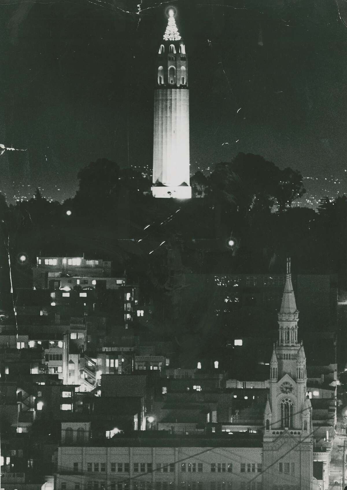 Coit Tower is adorned and lit for Christmas, December 22, 1970. Saints Peter and Paul Church is seen in the foreground.
