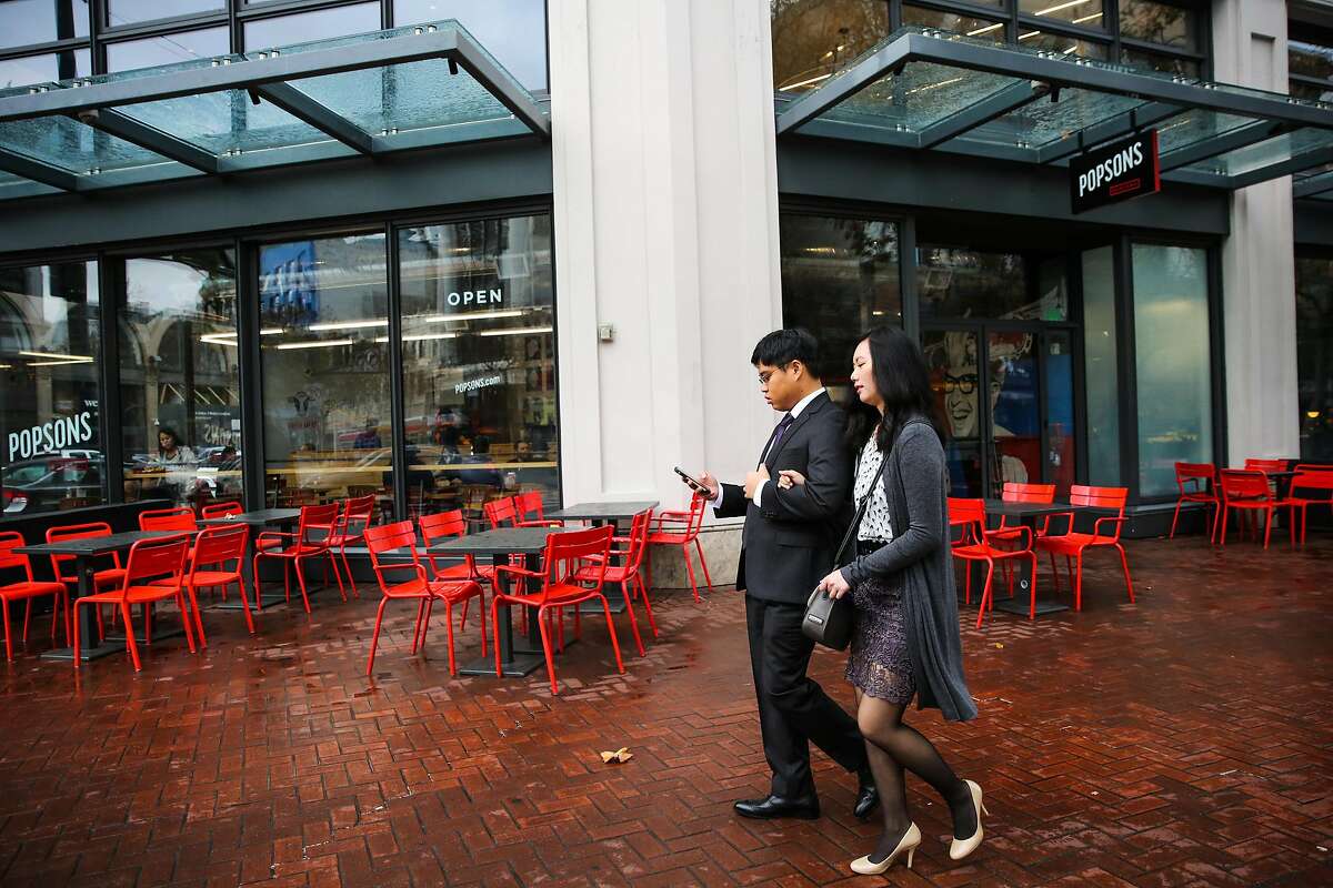 Pedestrians walk past Popsons Burgers after a rainstorm, on Market Street, in San Francisco, California, on Wednesday, November 30, 2016.