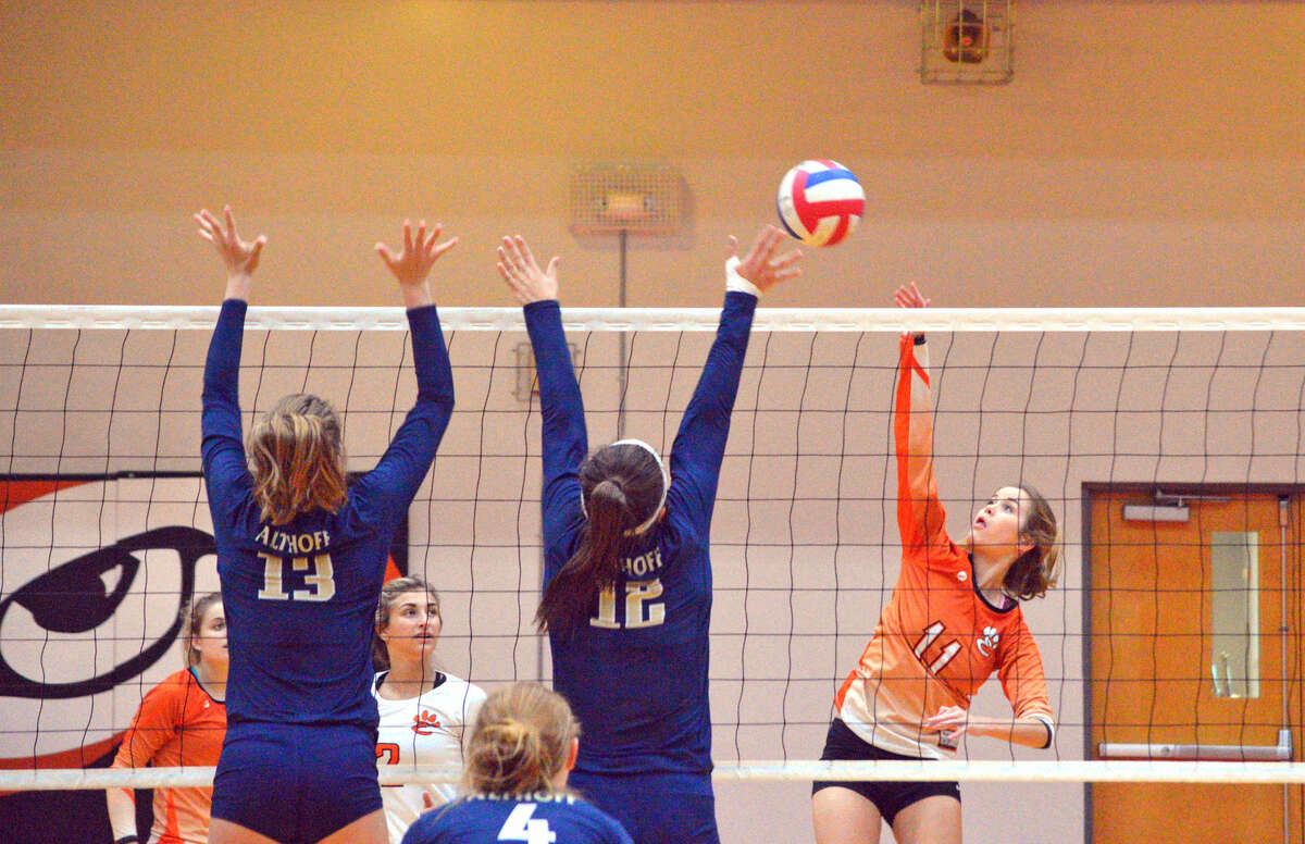 Edwardsville senior Shelby Saye tries to hit the ball over a pair of Althoff players during Tuesday’s match at EHS.