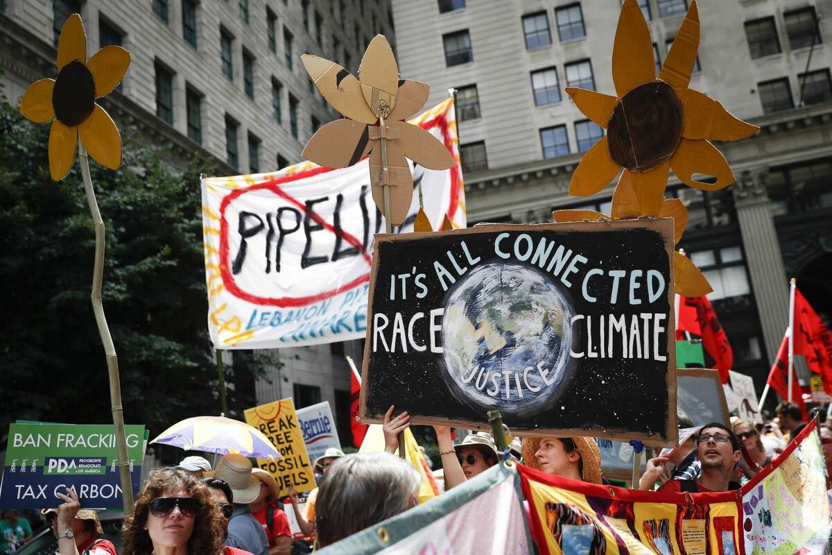 In this Sunday, July 24, 2016 file photo, climate change activists carry signs as they march during a protest in downtown in Philadelphia a day before the start of the Democratic National Convention. Matthew Nisbet, a communications professor at Northeastern University, says the split with science is most visible and strident when it comes to climate change because the nature of the global problem requires communal joint action, and for conservatives thats especially difficult to accept. He and other experts say climate change is more about tribalism, or who we identify with politically and socially. Liberals believe in global warming, conservatives dont. (AP Photo/John Minchillo)