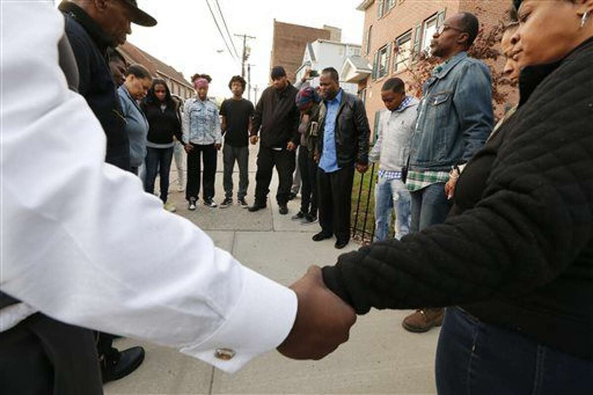 Neighbors hold hands in prayer after three people were killed and several others injured in a stabbing at a house in Newark, N.J. Saturday, Nov. 5, 2016. The stabbings occurred around 4 p.m. Saturday at a Hedden Terrace residence. Essex County's major crimes task force and city police are investigating the stabbings. (Robert Sciarrino/NJ Advance Media for NJ.com via AP)