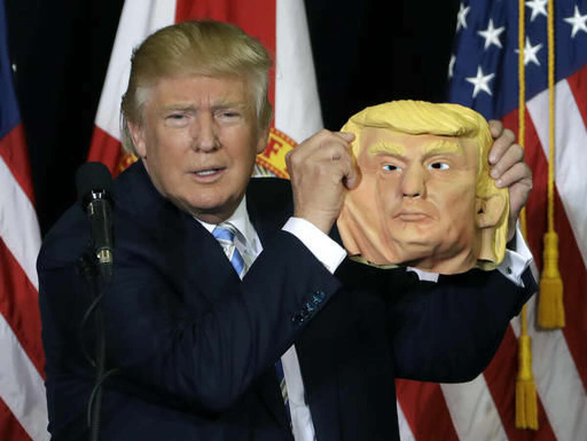 Republican presidential candidate Donald Trump holds up a Donald Trump mask during a campaign speech, Monday, Nov. 7, 2016, in Sarasota, Fla. (AP Photo/Chris O'Meara)
