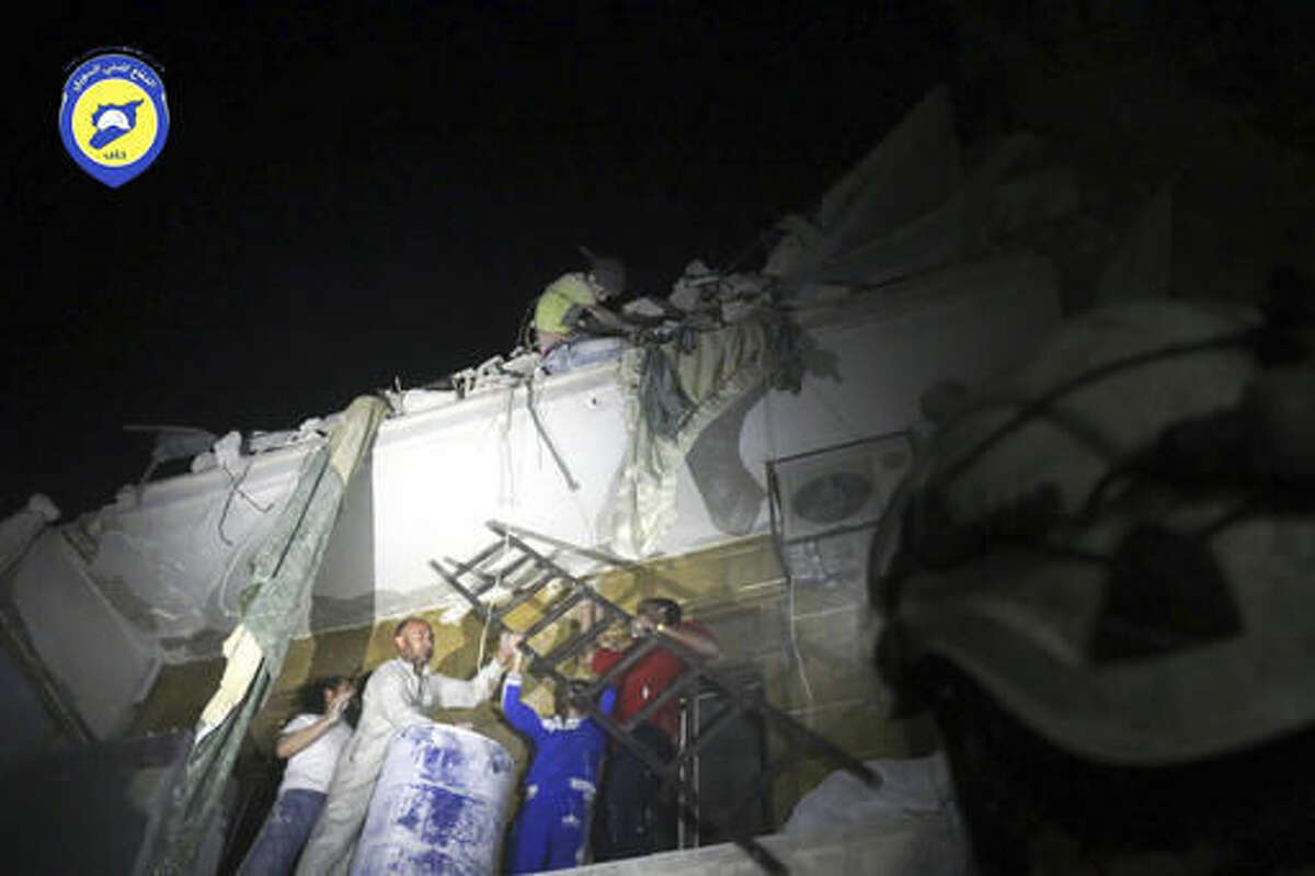 In this photo released early Monday, Oct. 17, 2016 and provided by the Syrian Civil Defense group known as the White Helmets, rescue workers try to remove a boy stuck in the debris of a building in the neighborhood of Qaterji in rebel-held east Aleppo following an airstrike in Aleppo, Syria. Syrian activists are reporting that airstrikes on a rebel-held, eastern neighborhood in the city of Aleppo have killed at least 13 people, including children. The Britain-based Syrian Observatory for Human Rights says the airstrikes hit the Marjeh neighborhood. (Syrian Civil Defense White Helmets via AP)
