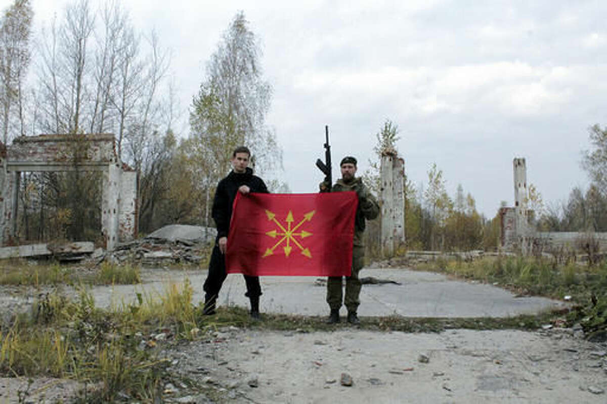 In this photo taken Friday, Aug. 19, 2016, participants at a ultra-nationalist "war camp" hold the flag of the Eurasianist movement, used by the Eurasian Youth Movement, on the outskirts of Moscow, Russia. Camps such as these have been on the rise in Russia, with some serving as breeding grounds for the volunteers who fought with Russia-backed separatists in eastern Ukraine. (AP Photo/Natalya Makeeva)