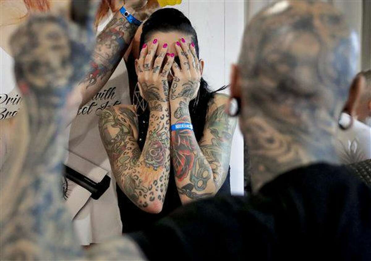 In this picture taken on Sunday, Oct. 16, 2016, a a woman covers her face during the International Tattoo Convention Bucharest 2016 in Bucharest, Romania. More than 100 tattoo and piercing artists brought their skills and art to a three-day convention in the Romanian capital.(AP Photo/Vadim Ghirda)