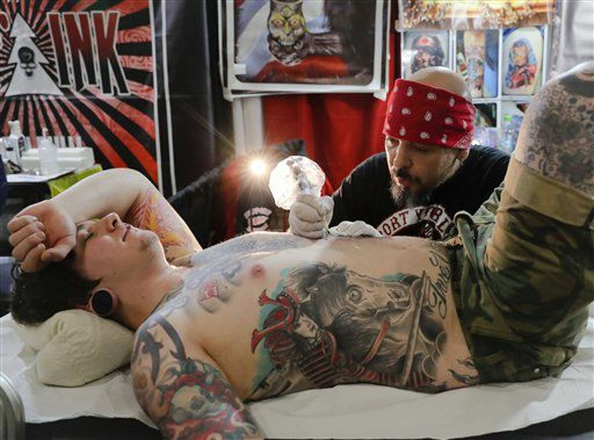 In this picture taken on Sunday, Oct. 16, 2016, a man gets a tattoo during the International Tattoo Convention Bucharest 2016 in Bucharest, Romania. More than 100 tattoo and piercing artists brought their skills and art to a three-day convention in the Romanian capital.(AP Photo/Vadim Ghirda)