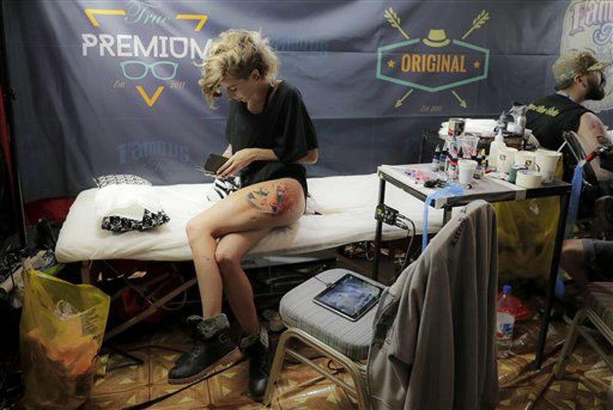 In this picture taken on Sunday, Oct. 16, 2016, a woman takes a break from getting a tattoo during the International Tattoo Convention Bucharest 2016 in Bucharest, Romania. (AP Photo/Vadim Ghirda)