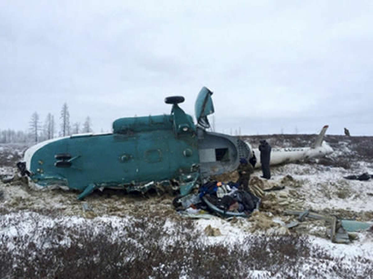 In this handout photo, made available by Russian Emergency Situations Ministry, Saturday, Oct. 22, 2016, a Mi-8 helicopter lies on the ground after it crashed about 45 kilometers (28 miles) northeast of Staryi Urengoi in Hassana, Russia. Russia's aviation agency says 19 people have died after a helicopter carrying oil workers crashed. (Russian Ministry for Emergency Situations photo via AP)