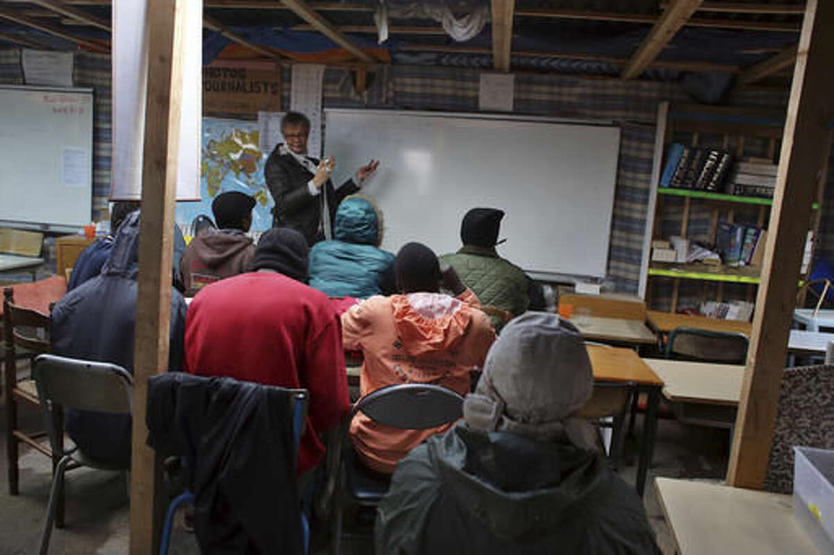 Volunteer teacher Laurence teach French to migrants in a classroom at a makeshift migrant camp near Calais, France, Saturday, Oct. 22, 2016. French authorities say the closure of the slum-like camp in Calais will start on Monday and will last approximately a week in what they describe as a "humanitarian" operation. (AP Photo/Thibault Camus)