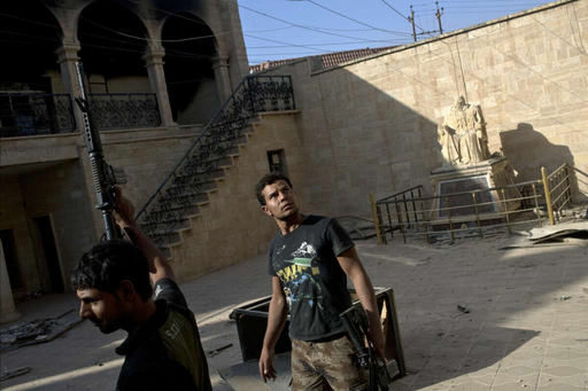 Iraqi security forces look around the courtyard of the church of Saint Shmoni, damaged by Islamic State fighters, in Bartella, Iraq, Saturday, Oct. 22, 2016. Iraqi forces retook the town of Bartella, around 15 kilometers east of Mosul, earlier this week, but are still facing pockets of resistance in the area. (AP Photo/Marko Drobnjakovic)