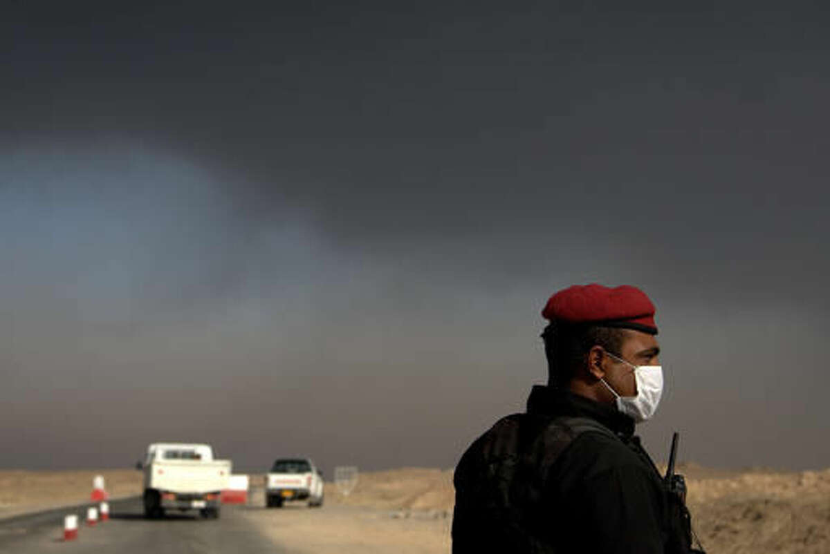 A member of the Iraqi special forces guards a checkpoint near the village of Awsaja, Iraq, as smoke from fires lit by Islamic State militants at oil wells and a sulfur plant fill the air on Saturday, Oct. 22, 2016. U.S. military officials say that a fire at the sulfur plant in northern Iraq is creating a potential breathing hazard for American forces and other troops at a logistical base south of Mosul. (AP Photo/Adam Schreck)
