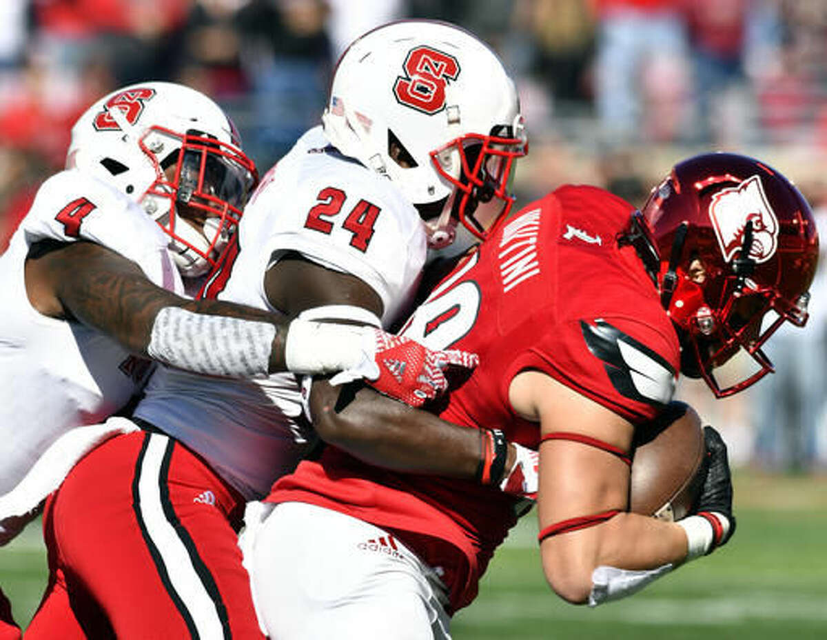 Louisville's Cole Hikutini (18) is brought down by North Carolina State's Shawn Boone (24) and Jerod Fernandez (4) during the first half of their NCAA college football game, Saturday, Oct. 22, 2016, in Louisville, Ky. (AP Photo/Timothy D. Easley)