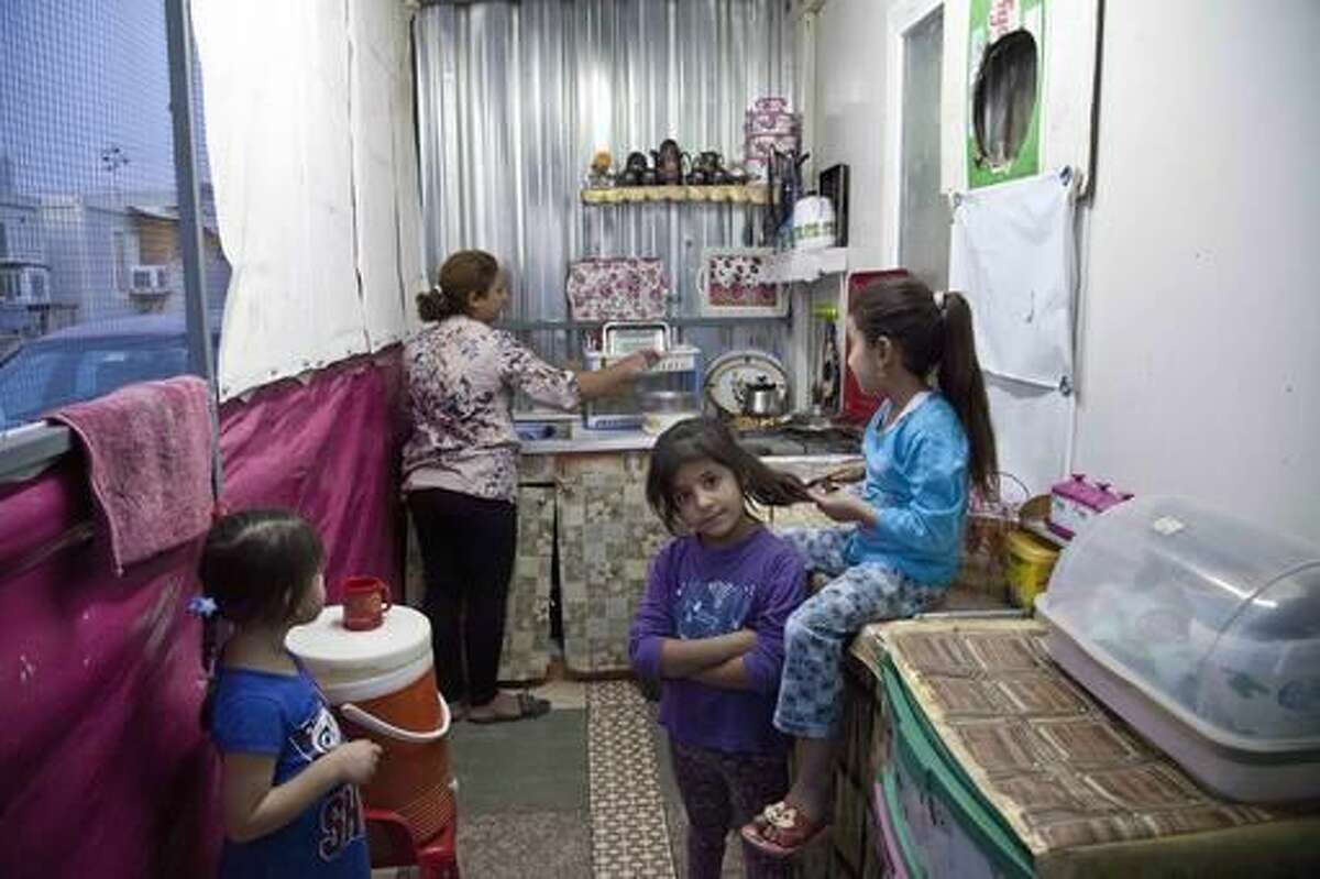 Intisar Mateh, second left, washes the dishes as her daughter, Farah Mateh, right, plays with her friends in a camp for displaced Christians in Irbil, Iraq, Friday, Oct. 21, 2016. Iraqi refugees from areas near Mosul are eagerly following the offensive to drive the Islamic State group from the city and hope to return to their homes, but they also fear what they might find there. (AP Photo/Fay Abuelgasim)