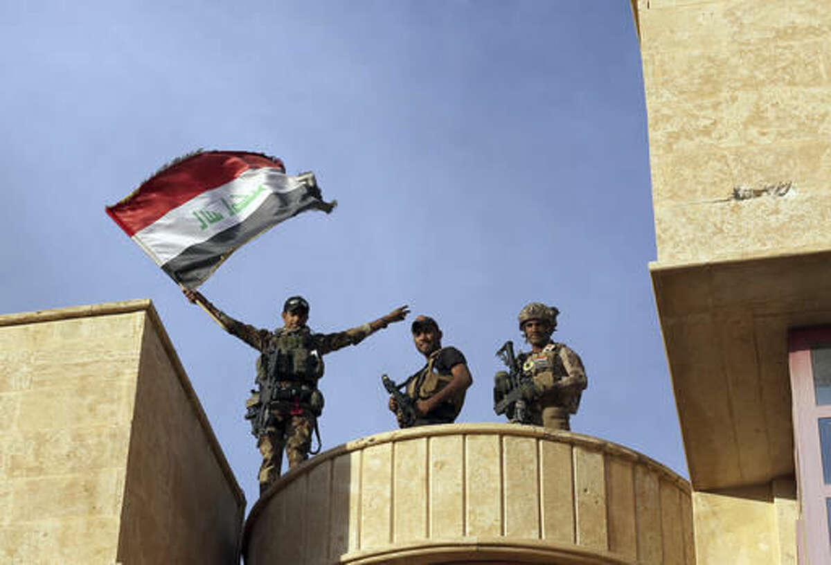Iraq's elite counterterrorism forces raise an Iraqi flag after retaking Bartella, outside Mosul, Iraq, Friday, Oct. 21, 2016. Iraqi and Kurdish forces backed by a U.S.-led coalition launched a multi-pronged assault this week to retake Mosul and surrounding areas from Islamic State militants. The operation is the largest undertaken by the Iraqi military since the 2003 U.S.-led invasion. Iraqi officials said they had advanced as far as the town of Bartella, 15 kilometers (nine miles) from Mosul's outskirts, by Thursday. (AP Photo/ Khalid Mohammed)