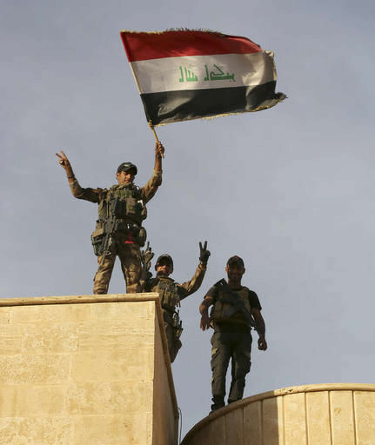 Iraq's elite counterterrorism forces raise an Iraqi flag after retaking Bartella, outside Mosul, Iraq, Friday, Oct. 21, 2016. Iraqi and Kurdish forces backed by a U.S.-led coalition launched a multi-pronged assault this week to retake Mosul and surrounding areas from IS. The operation is the largest undertaken by the Iraqi military since the 2003 U.S.-led invasion. Iraqi officials said they had advanced as far as the town of Bartella, 15 kilometers (nine miles) from Mosul's outskirts, by Thursday. (AP Photo/ Khalid Mohammed)