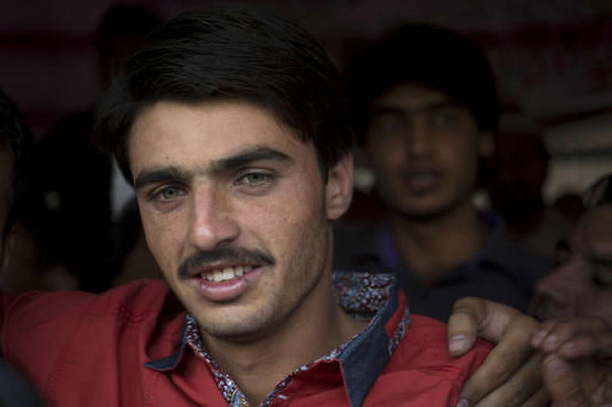 Pakistani tea vendor Arshad Khan, 18, center, is surrounded by shopkeepers and colleagues at a market where he sells tea in Islamabad, Pakistan, Friday, Oct. 21, 2016. Khan, who saw his life change overnight after a picture of him at work went viral, said Friday he was totally unaware of social media until recently when boys and girls suddenly started thronging a flea market in Islamabad to take selfies with him.(AP Photo/B.K. Bangash)