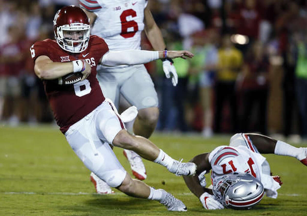 FILE - In this Sept. 17, 2016, file photo, Oklahoma quarterback Baker Mayfield (6) fights off a tackle by Ohio State linebacker Jerome Baker, right, during an NCAA college football game in Norman, Okla. Mayfield came into the season as one of the big-name returning stars getting Heisman hype. Losing two September games pretty much ended that talk, but Mayfield might still have a chance to get the invitation to New York he probably deserved last season. (AP Photo/Sue Ogrocki, File)
