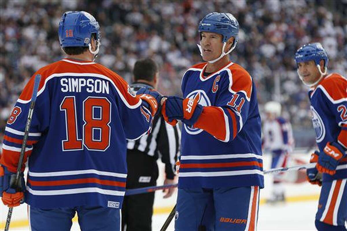 Former Edmonton Oilers' Craig Simpson (18) and Mark Messier (11) celebrate Messier's goal against the Winnipeg Jets during the first period of the NHL Heritage Classic alumni game, Saturday, Oct. 22, 2016, in Winnipeg, Manitoba. (John Woods/The Canadian Press via AP)