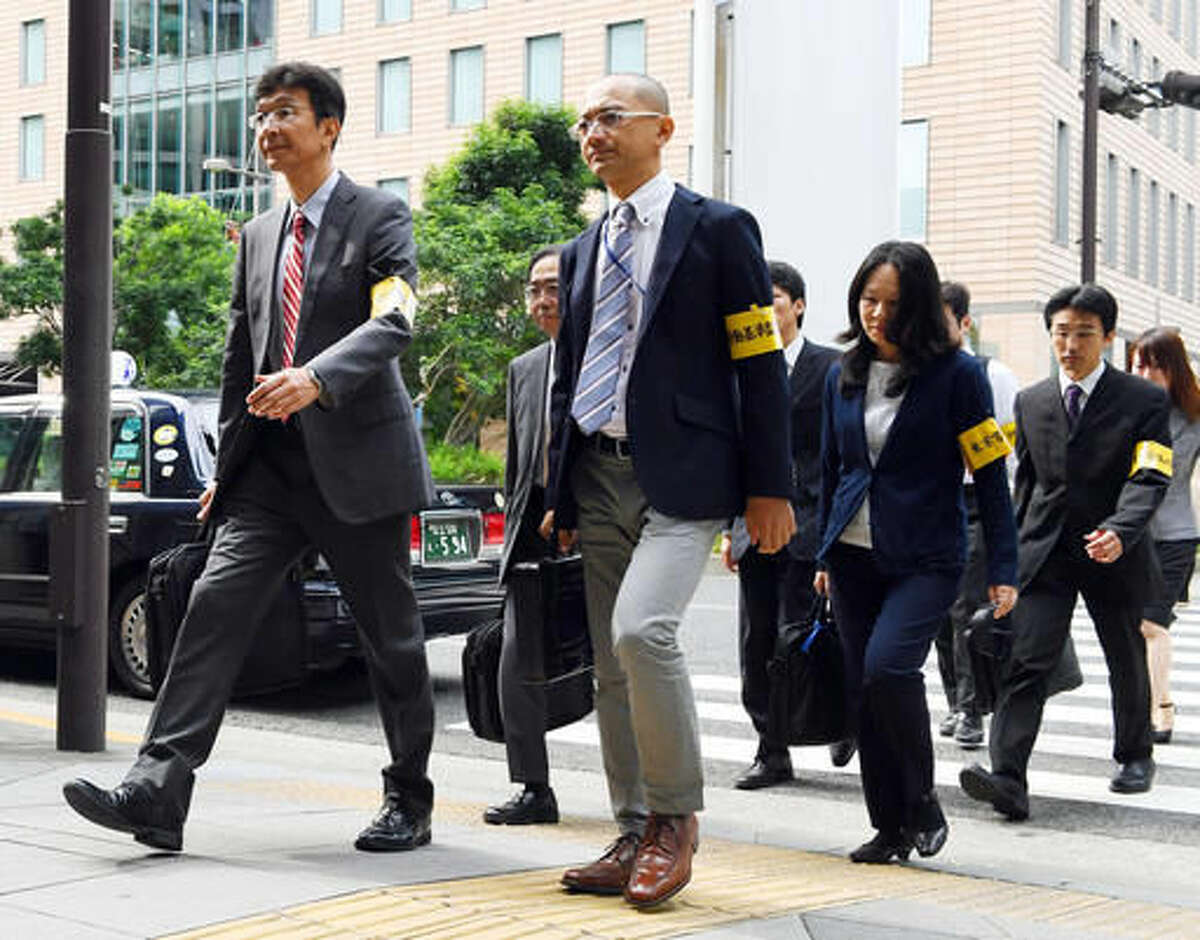 In this Oct. 14, 2016 photo, officials from the Tokyo Labor Bureau head to the headquarters of Japan’s top ad agency, Dentsu, in Tokyo for on-site inspections. Matsuri Takahashi’s dream career at Dentsu ended with her suicide after her overtime exceeded 100 hours a month. (Akiko Matsushita/Kyodo News via AP)