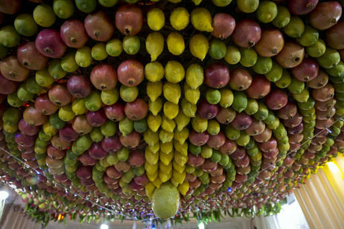In this Sunday, Oct. 16, 2016 photo, a traditional fruit canopy is displayed at the house of Abdullah Wasef Tawfiq, the high priest of the ancient Samaritan community, during celebrations of the week-long biblical holiday of Sukkot, or Feast of Tabernacles, on Mount Gerizim, overlooking the West Bank city of Nablus. In the Bible, God commands the people of Israel to build huts symbolizing the Israelites’ encampments as they wandered the desert following the exodus from Egypt. Unlike the outdoor huts Jews construct on the holiday, Samaritans build exquisite canopies of densely packed fruit, which are attached to metal frames and perched on stilts or suspended from living room ceilings. (AP Photo/Nasser Nasser)