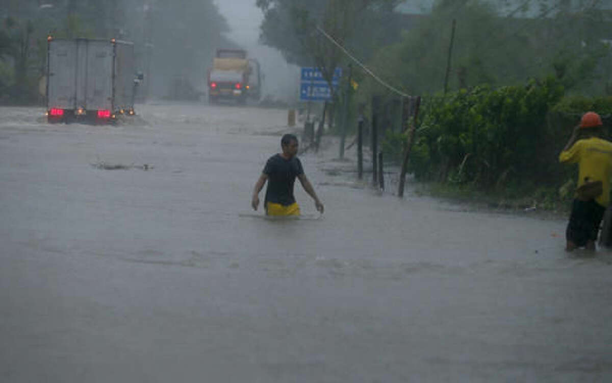 A man wades through a flooded highway at the height of Super Typhoon Haima that lashes Narvacan township, Ilocos Sur province in northern Philippines Thursday, Oct. 20, 2016. Super Typhoon Haima slammed into the northeastern Philippine coast late Wednesday with ferocious winds and rain that rekindled fears and memories from the catastrophe wrought by Typhoon Haiyan in 2013. (AP Photo/Bullit Marquez)