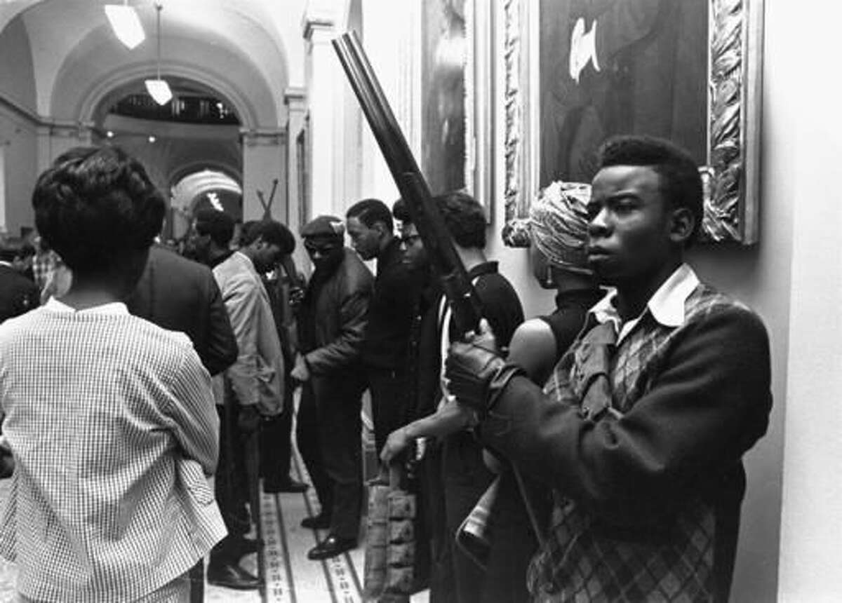FILE - In this May 2, 1967 file photo, armed members of the Black Panthers Party stand in the corridor of the Capitol in Sacramento, Calif. Hundreds of former Black Panthers from around the world are expected to gather in Oakland, California, for a four-day conference that started Thursday, Oct. 20, 2016. The Panthers emerged from the gritty city 50 years ago, declaring a new party dedicated to defending African-Americans against police brutality and protecting their rights. (AP Photo/Walt Zeboski, File)
