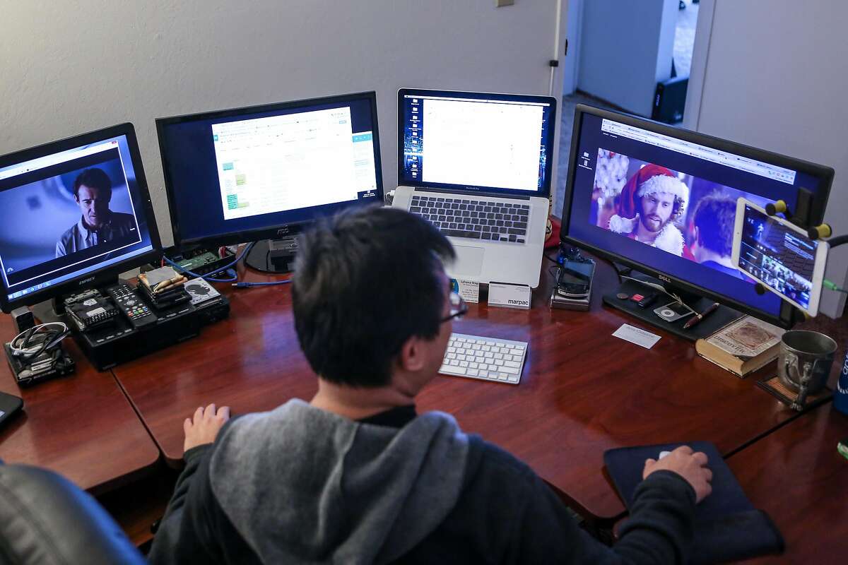 Francis Kong watches TV shows in between working on two out of the six screens he has set up in his home office on Friday, December 2, 2016 in Alameda, Calif.