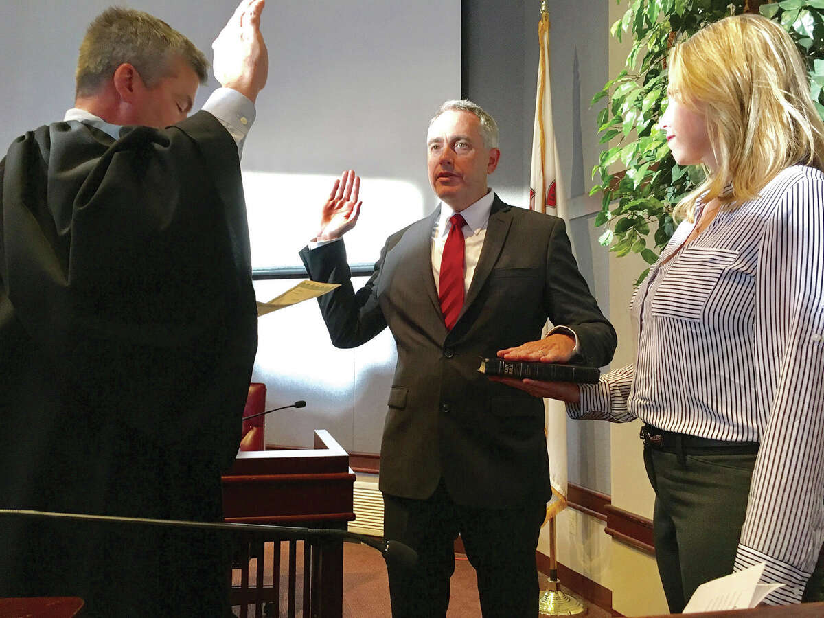 Madison County State's Attorney Tom Gibbons, center, is sworn in by Judge William Mudge. At right is Gibbons' wife Lori.