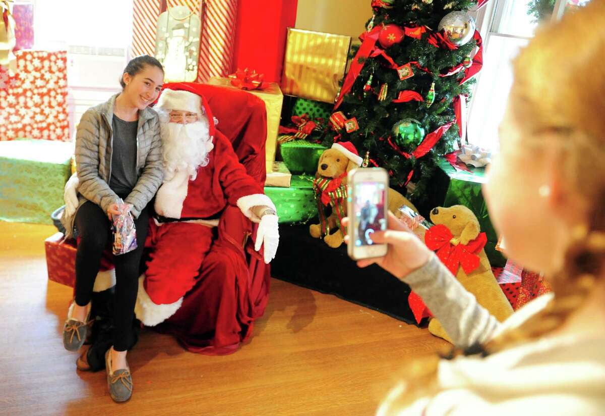 Megan Sullivan, left, visits Santa as Samantha Swidler, 12, snaps a photo during the 31st Annual "A Visit to Santa?’s House" held at the historic Burr Homestead in Fairfield, Conn. on Saturday Dec. 3, 2016. Some of the activities include holiday art & crafts, a bake sale, face painting, performances by Flash Pointe Dance and much more. The event continues Sunday from 10 am to 2 pm. The Junior Women?’s Club of Fairfield host the event along with sponsor Newman's Own. Proceeds to benefit Healing Tree Economic Development.
